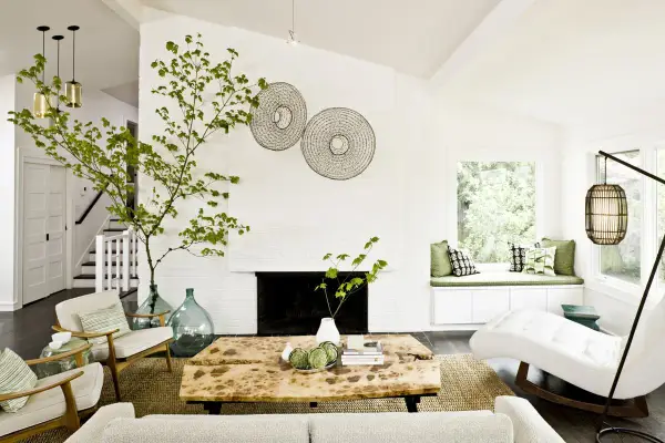 Ideas para decorar ramas secas: una rama verde decora el salón moderno con chimenea, mesa de madera y sillones.