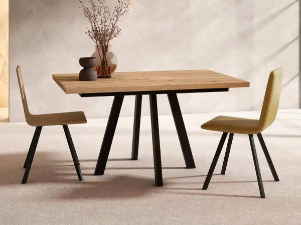 Mesa comedor extensible de madera con patas metálicas negras, ideal para ampliar el espacio. Dos sillas modernas flanquean la mesa.