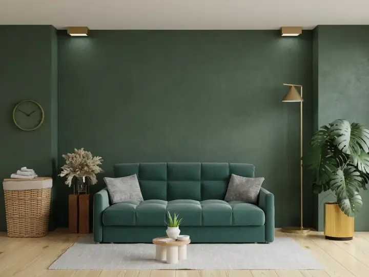 Un acogedor salón con un sofá verde, plantas y una lámpara dorada.